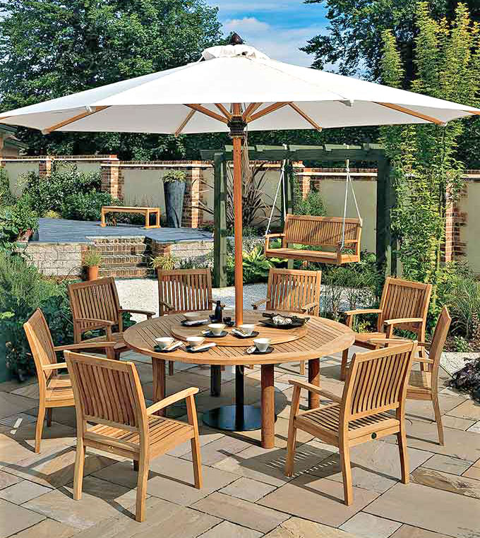 Teak outdoor dining set with umbrella hole under a pergola